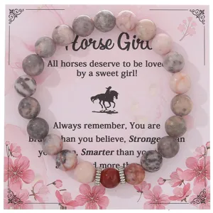 Dettaglio in primo piano del bracciale di perle in pietra zebrata rosa su carta floreale.