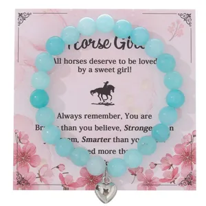 Bracciale di perle in pietra azzurra con ciondolo a cuore su carta ispiratrice cavallo.