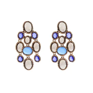 Vue détaillée de boucles d'oreilles pendantes vintage dorées avec des pierres bleues et blanches.