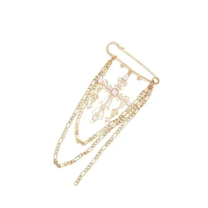 Primer plano detallado del broche de cruz vintage dorado con cadenas y perlas finas.