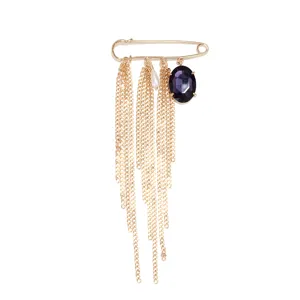 Primer plano de un broche retro dorado con cadena múltiple, cristal morado y perla elegante.
