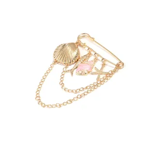 Gouden maritieme veiligheidsspeld broche met schelp zeester hanger en gelaagde kwastkettingen.