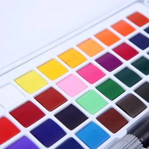 Close up detail view of colorful solid watercolor paint pan set with a water brush.
