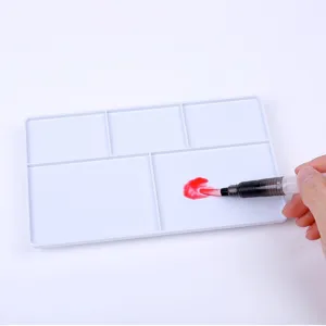 Detailed view of white plastic watercolor mixing palette tray with a water brush tool.