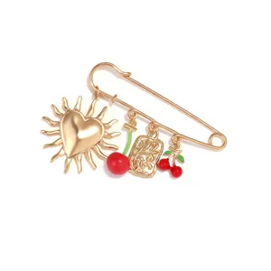 Gold alloy safety pin brooch detail featuring sun heart and cherry charms, cute style.