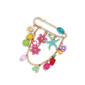Close-up detail of cute colorful enamel starfish chili and flower charm safety pin brooch jewelry.