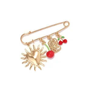 Close-up detail of the gold-tone alloy cherry and heart sun charm safety pin brooch jewelry.