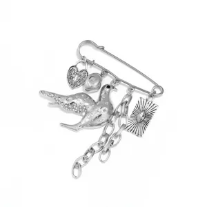 Gedetailleerde close-up van een punk zilveren duif broche met kettingen, hangslot en strass.