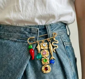 Detailed shot of retro gold-tone safety pin brooch with colorful charms and crystals.