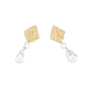 Vista detallada de pendientes de oro texturizados vintage con colgantes de perlas barrocas.