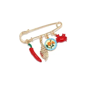 Vue détaillée d'une broche épingle de sûreté dorée avec de charmants pendentifs en émail.