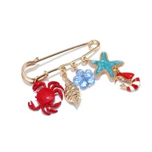Broche épingle de sûreté dorée avec des charmants motifs marins de plage et une belle étoile mer.