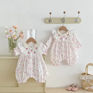 Grenouillère en coton pour bébé fille avec col en dentelle délicat et imprimé floral rose.