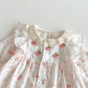 Détail barboteuse bébé fille coton, broderie florale douce, col en dentelle, manches longues.