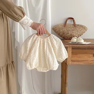 Primo piano della tutina per neonato testurizzata a maniche lunghe color crema.