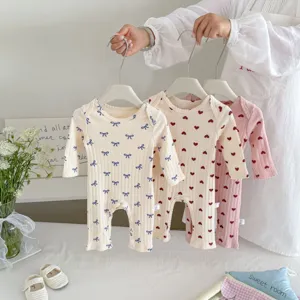 Detailed view of cute cotton baby rompers with lovely bow and heart prints for infant daily wear.