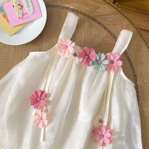 Dettaglio abito estivo con bretelle per neonati, tutina leggera con fiori in tessuto colorato.