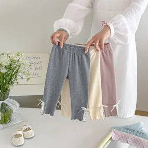 Gedetailleerd overzicht van schattige meisjesleggings met delicate kantzoom en zoete strikjes.