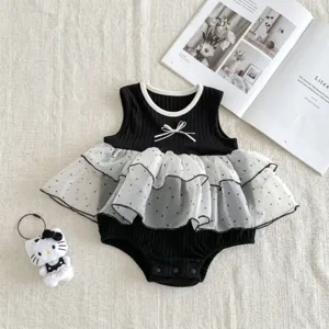 Detail view of infant baby girl black romper featuring delicate white bow and layered polka-dot mesh skirt.