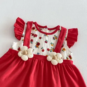 Dettaglio del vestito estivo rosso da bambina con fiori e volant adorabili e unici.