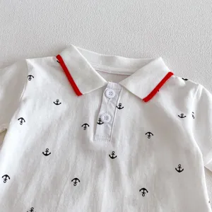 Infant baby polo collar romper detail shot, white fabric with black anchor pattern and red trim.