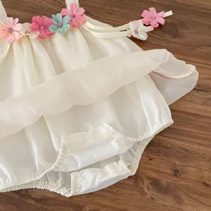 Dettaglio tutina estiva in tulle per neonati, spallina floreale, tessuto morbido e leggero.