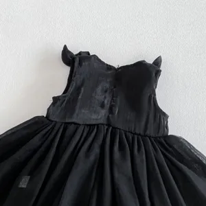 Detalle de vestido de tul negro para bebé con corpiño texturizado y elegantes lazos.