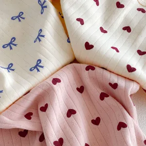 Soft ribbed cotton fabric detail with cute heart and bow prints for baby clothes.