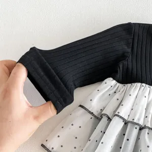 Infant baby girl dress detail shot, black ribbed long sleeve and white polka dot mesh layer.