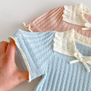 Close-up detail of knitted girls short sleeve top with hollow collar and cute bow decoration.