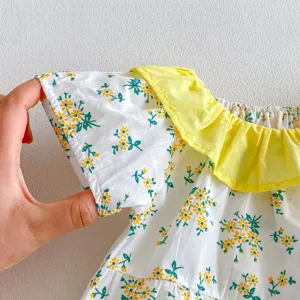 Primer plano de la manga y el cuello con volantes amarillo del pelele floral para bebé niña.