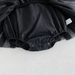 Detalle de mameluco de tul negro para bebé con broches y etiqueta de lavado de verano.