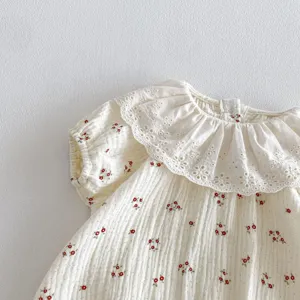 Close up detail view of infant baby cotton gauze short sleeve romper with lace collar.
