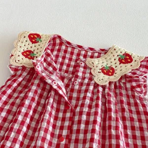 Vista dettagliata della romper per neonata a quadri rossi con colletto fragola all'uncinetto.
