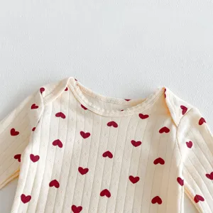 Close-up detail of infant baby long sleeve cotton romper featuring cute red heart prints.