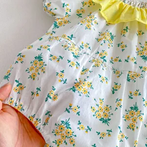 Detalle de mameluco floral para niña con cuello amarillo y textura de tela suave.