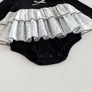 Detail shot of infant baby girl black romper featuring layered white polka-dot mesh ruffles.
