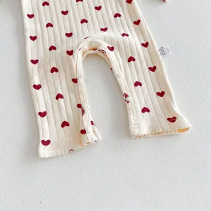 Close-up of baby ribbed romper detail, soft cotton fabric with cute red heart prints and snaps.