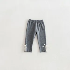 Grijze baby meisjes legging met delicate witte kant en strikdetails bij de boorden, casual stijl.