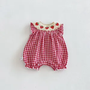 Vista dettagliata della tutina a quadri rossa da bambina con colletto all'uncinetto e fragole.
