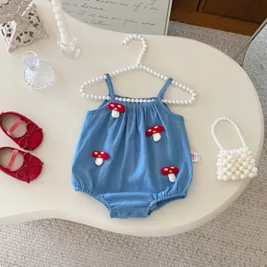 Detalle de mameluco de verano para bebé azul con parches de hongos y percha de perlas.