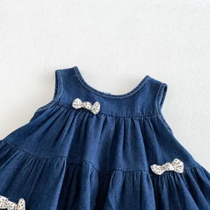Dettaglio abito di jeans per neonata, gonna a balze smanicata con dolci fiocchi decorativi chic.