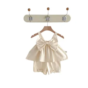 Adorable baby girl summer clothing set featuring a large bow and beige two-piece outfit.