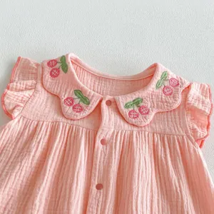 Baby pink gauze romper detail, cute cherry embroidery, peter pan collar close-up shot.