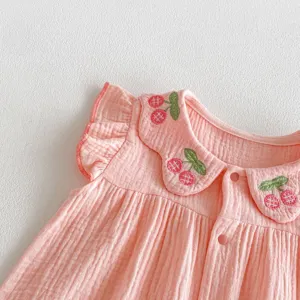 Close-up of pink baby romper detail featuring cute cherry embroidery and sweet ruffled collar.