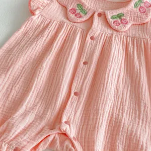 Cute baby girl pink gauze romper with embroidered cherry collar and front snap buttons detail.