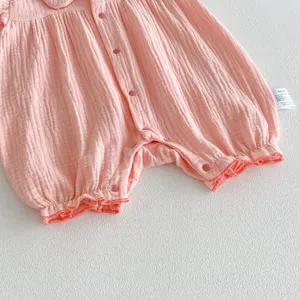 Detail shot of pink baby cotton romper, featuring snap buttons and soft fabric texture.