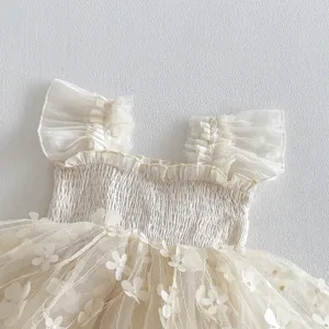 Primo piano sui dettagli dell'abito in tulle per neonata con corpetto arricciato e fiori 3D.