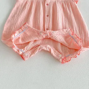 Baby pink romper detail shot, soft cotton material with cute ruffles and snap buttons.