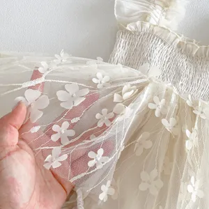 Dettaglio abito da neonata in tulle con fiori 3D squisito, tessuto trasparente morbido.